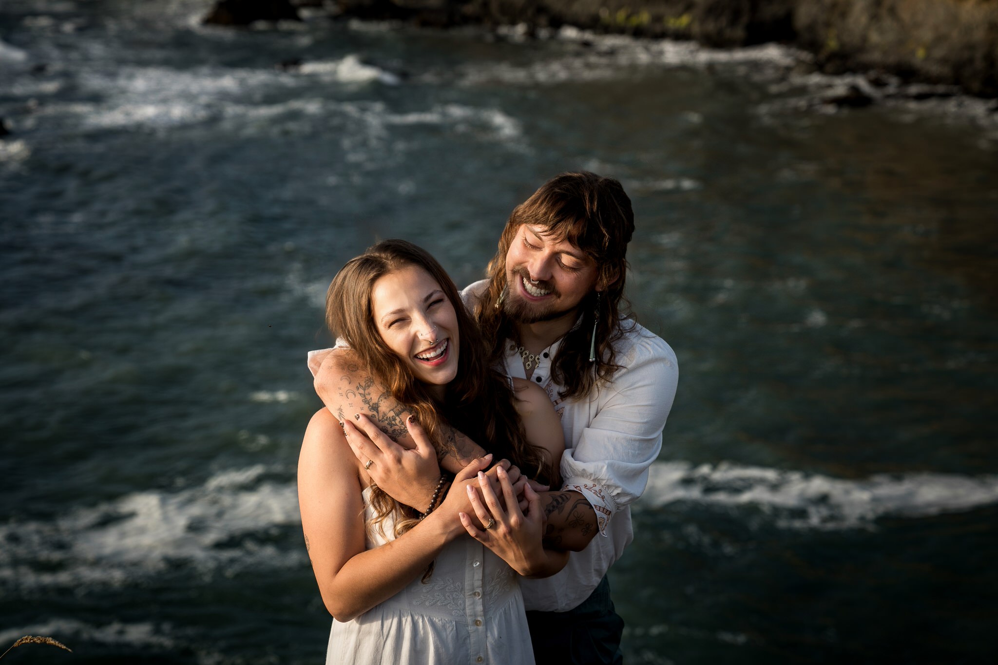 Couple laughing together on rocks above the ocean at Elk Head Trail