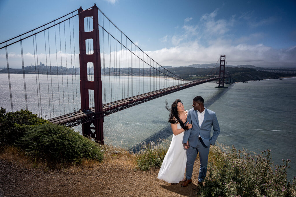 Interracial couple posing for engagement photo in front of Golden Gate Bridge in San Francisco, California