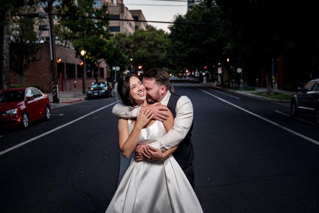 Bride and groom laughing together in the street outside The Sterling Hotel at dusk