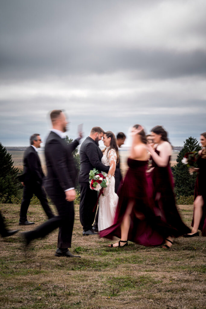 Bride and groom sharing a quiet moment while wedding party moves around them at North Coast Hitching Post