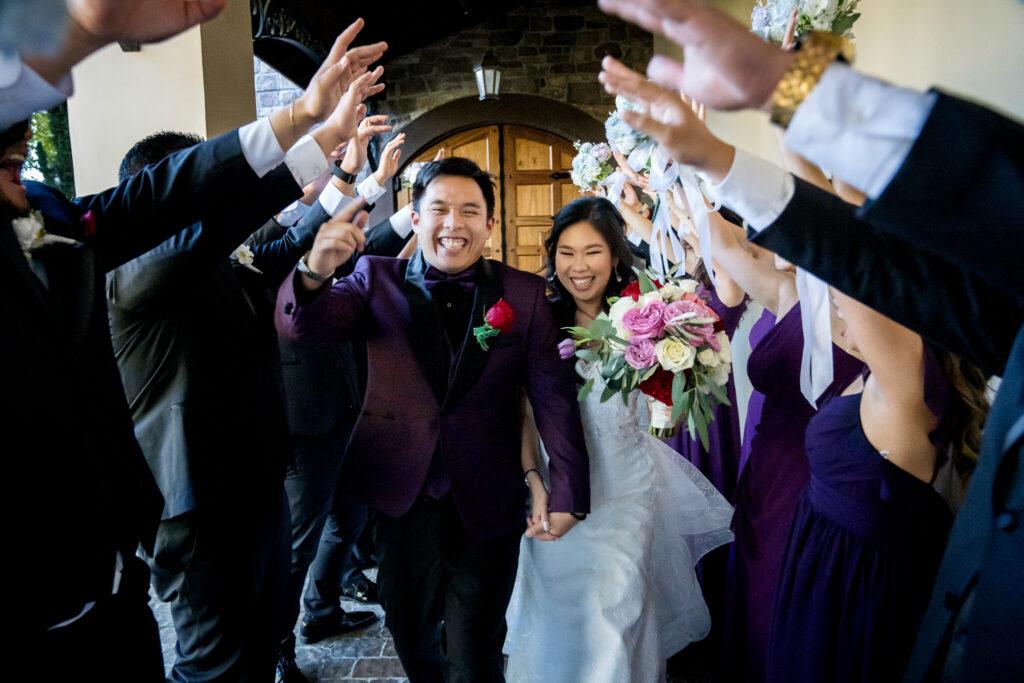 Alt Text: Bride and groom smiling while their bridal party cheers them on at Casa Real