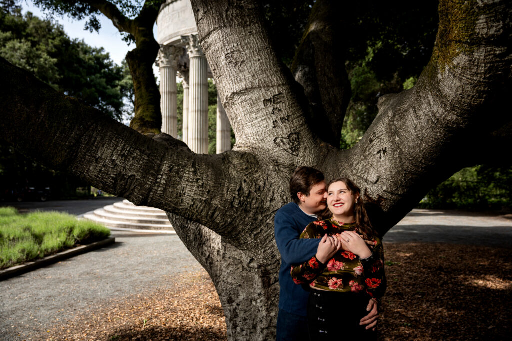 Couple laughing beneath a large oak tree near the Pulgas Water Temple