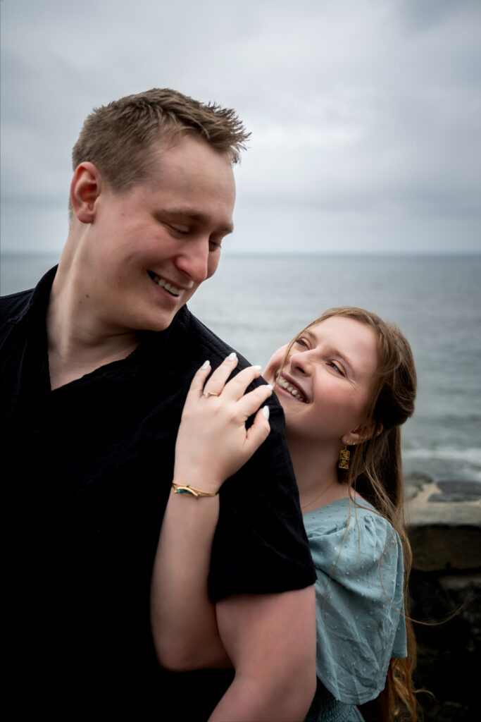 Couple laughing together with the ocean behind them at Wedding Rock