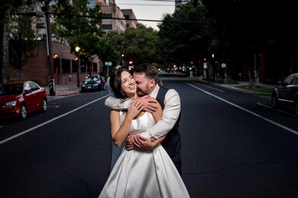 Bride and groom embracing in the street at night outside the Sterling Hotel in Sacramento, photographed by a Northern California wedding photographer