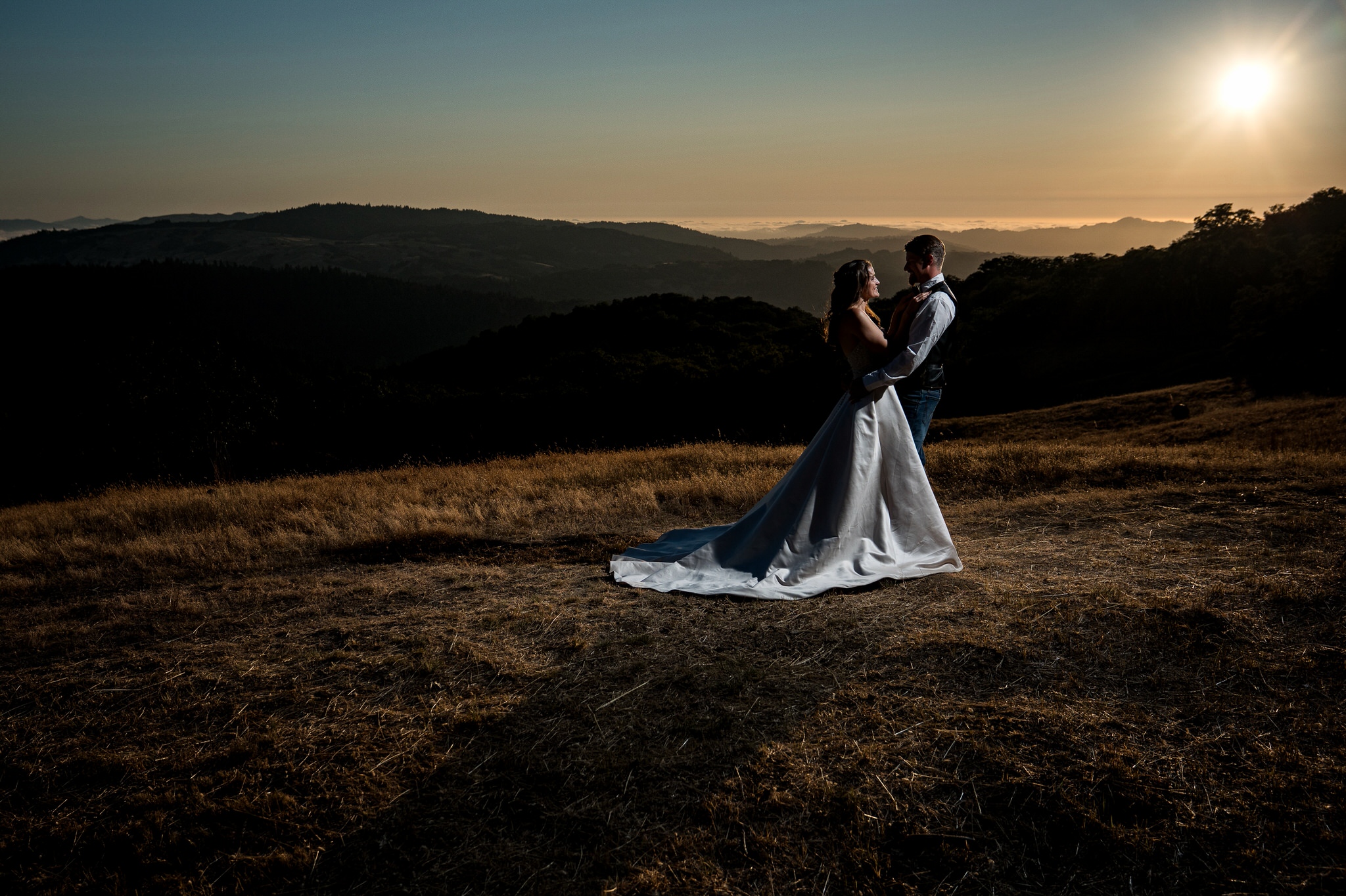Bride and groom embracing on a hilltop at golden hour on a private ranch near Showers Pass