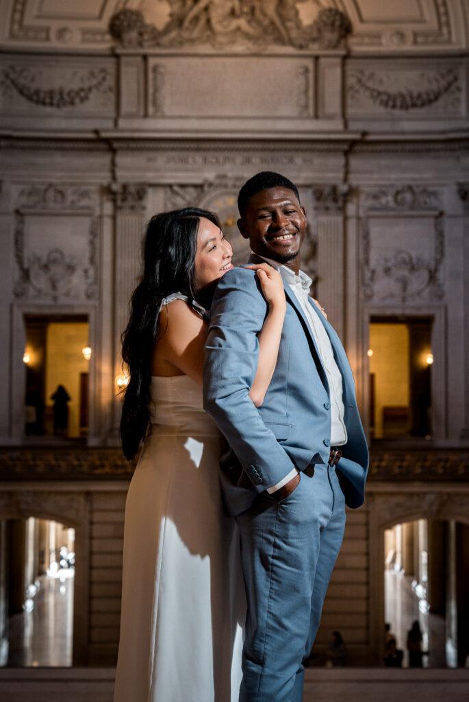 Couple in blush white and steel blue outfits inside the ornate interior at San Francisco City Hall