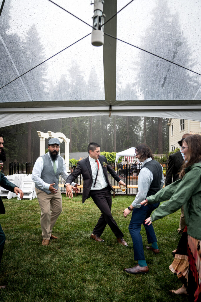 Groomen and wedding guests dancing under a rain-covered tent at Ridgefield in Arcata