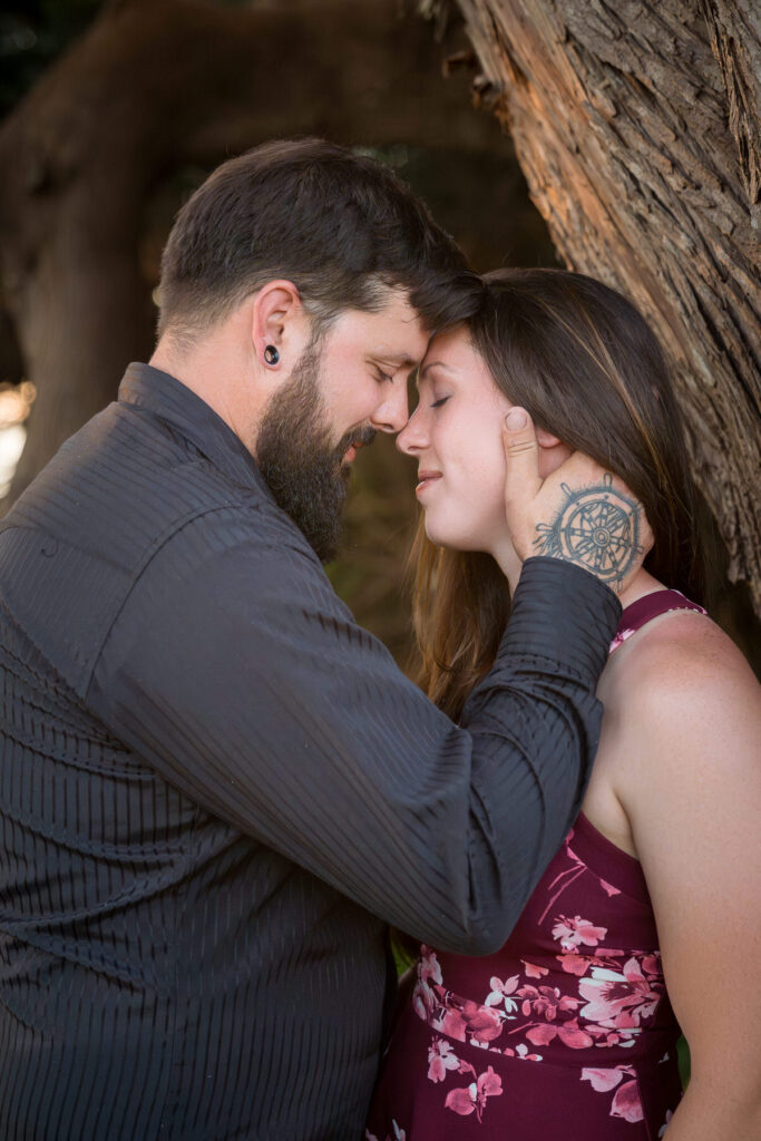 Emily and Dakota sharing an intimate moment with foreheads touching and eyes closed, showcasing their deep connection in a natural setting in Loleta, captured by Dan Berger Photography.