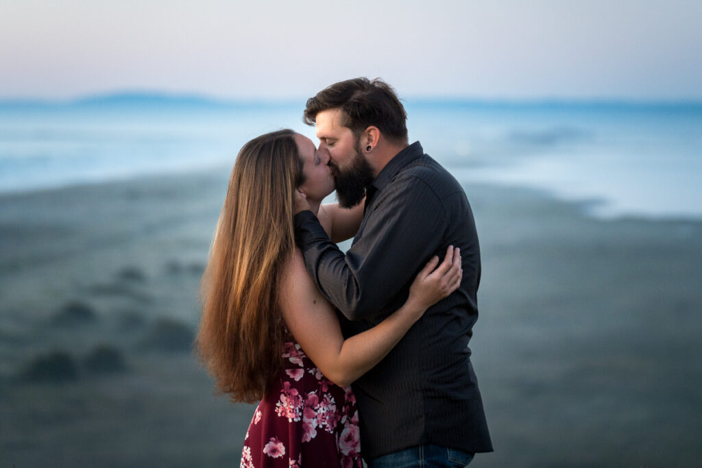 Emily and Dakota sharing a romantic kiss overlooking a serene beach at Loleta, with a soft, misty background enhancing the intimate moment, captured beautifully by Dan Berger Photography