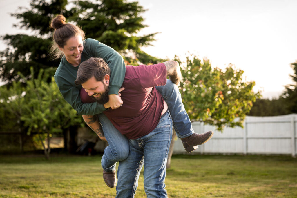 Emily joyfully piggybacking on Dakota in her dad's backyard in Hydesville, capturing a spontaneous, cheerful moment, perfectly embodying their playful and loving relationship, photographed by Dan Berger Photography.