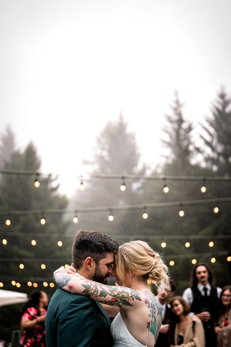 Bride and groom share their first dance under patio lights with foggy trees in the background at Ridgefield on Fickle Hill in Arcata, California.