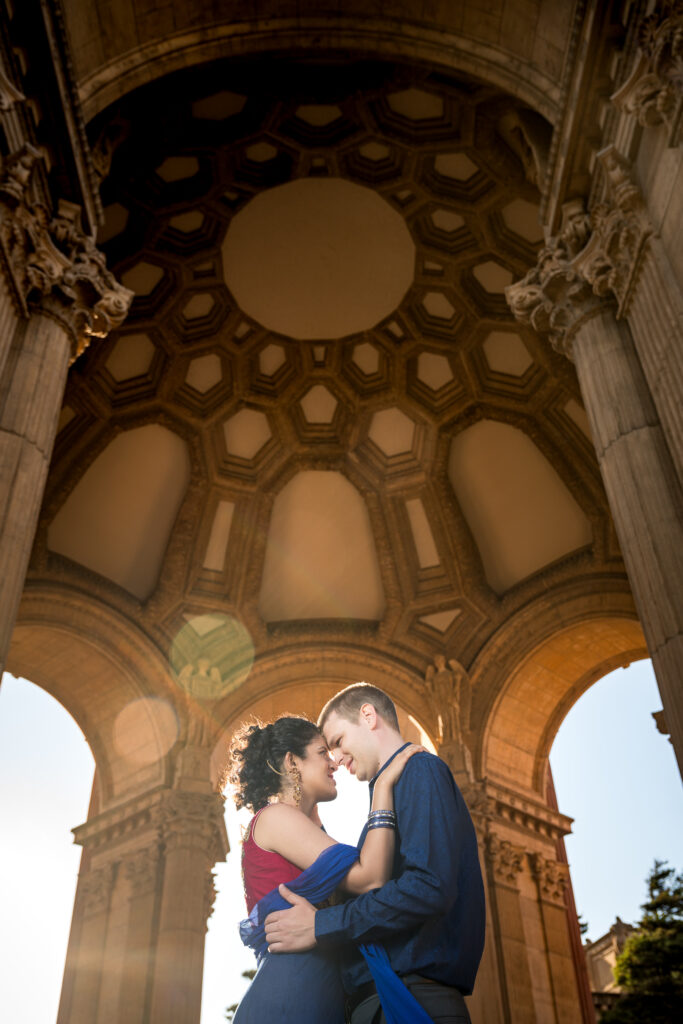 Couple embracing at the Palace of Fine Arts with the rotunda towering above them during their engagement session.