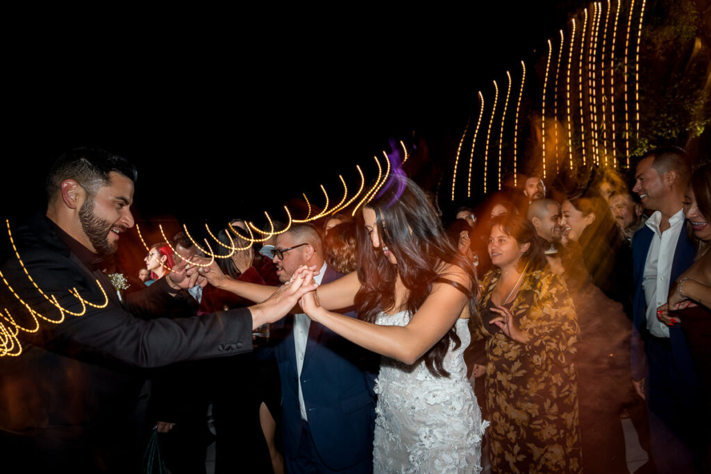 Bride and groom dancing together at Airola Road Vineyard in Murphys, CA, surrounded by guests with motion blur string lights creating a fun, dynamic party atmosphere.